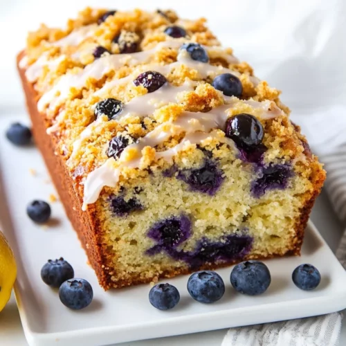 Lemon Blueberry Loaf: Moist, Easy, And Deliciously Healthy 2 Close-Up Of Lemon Blueberry Loaf Drizzled With Icing On A White Plate, Garnished With Fresh Blueberries.