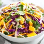 Bowl Of Mango Jicama Slaw Topped With Fresh Cilantro And Lime Wedges, Vibrant And Colorful.