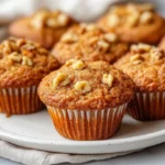 Freshly Baked Morning Glory Muffins On A White Plate, Garnished With Walnuts And Cinnamon