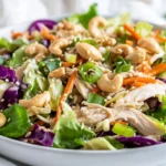 Vibrant Napa Chicken Salad In A White Bowl, Topped With Sesame Dressing And Garnished With Green Onions And Cashews
