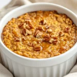 Bowl Of Pumpkin Baked Oatmeal Drizzled With Maple Syrup And Topped With Walnuts On A Simple Kitchen Towel.