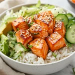 Salmon Rice Bowl With Seared Salmon, Jasmine Rice, Coleslaw, And Avocado Drizzled With Sriracha Mayo.