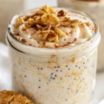 Bowl Of Snickerdoodle Overnight Oats With Crumbled Cookies And A Drizzle Of Maple Syrup On A Wooden Surface