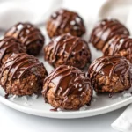 Vegan Chocolate Macaroons Drizzled With Dairy-Free Chocolate On A White Plate, Garnished With Shredded Coconut.