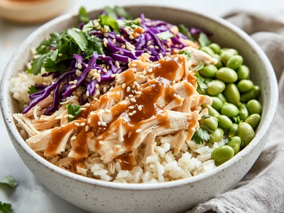 Nutritious And Delicious Asian Chicken Rice Bowl Recipe 2 Close-Up Of Asian Chicken Rice Bowl With Shredded Chicken, Edamame, And Coleslaw In A White Bowl