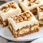 Bananas With Cream Cheese Frosting On A White Plate, Drizzled With Honey And Topped With Walnuts
