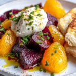 Vibrant Beet And Burrata Salad With Fried Bread On A White Plate, Garnished With Chives And Orange Segments.