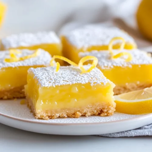 Best Lemon Bars With Shortbread Crust Perfected For Every Occasion 2 Best Lemon Bars With Shortbread Crust On A White Plate Dusted With Powdered Sugar And Garnished With Lemon Zest