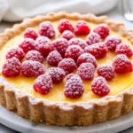 Best Lemon Tart On A White Plate, Topped With Raspberries And Dusted With Confectioners' Sugar