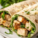 Healthy Chicken Caesar Wrap On A White Plate, Garnished With Parmesan Cheese And Fresh Basil