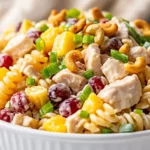 Creamy Chicken Cashew Pasta Salad With Rotini, Pineapple, And Grapes Served In A White Bowl, Garnished With Green Onions.