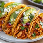 Colorful Chicken Tinga Tacos On A White Plate Garnished With Avocado, Cotija, And Cilantro