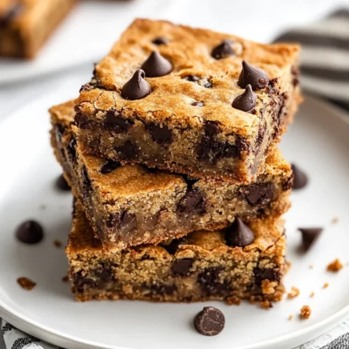 Delicious Chocolate Chip Banana Bread Bars Stacked On A White Plate Garnished With Crumbs And A Kitchen Towel