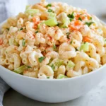 Bowl Of Classic Macaroni Salad Garnished With Hard-Boiled Egg And Paprika On A White Plate