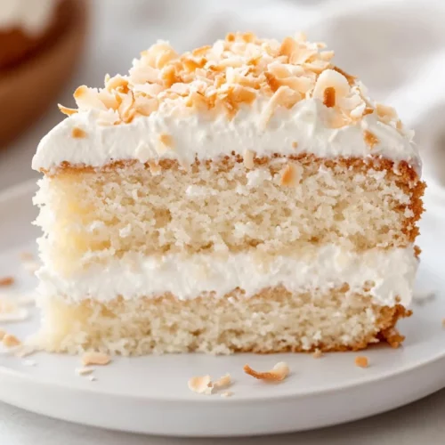 The Best Coconut Cream Cake Recipe For A Healthier Sweet Treat 2 Slice Of Coconut Cream Cake On A White Plate Topped With Whipped Cream And Toasted Coconut Shreds