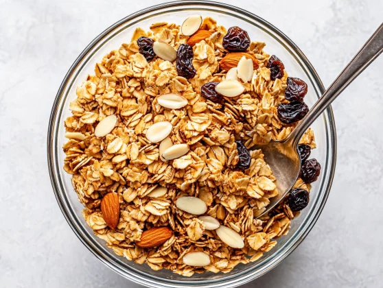 The Best Coconut Oil Granola Recipe Packed With Healthy Goodness 2 Bowl Of Coconut Oil Granola With Almonds, Pistachios, And Golden Raisins Surrounded By A Gray Kitchen Towel