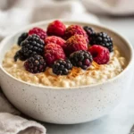 Bowl Of Easy Keto Porridge Topped With Fresh Berries And Keto Honey, Served On A White Ceramic Bowl