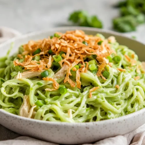 Bowl Of Green Ginger Rice Noodles Topped With Shredded Chicken And Crispy Shallots, Garnished With Green Onions