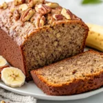 Freshly Sliced Healthy Banana Bread On A White Plate Garnished With Banana Slices And Nuts