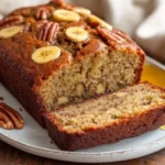 Slice Of Healthy Banana Bread Without Eggs On A White Plate, Drizzled With Honey And Sprinkled With Pecans.