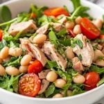 Herbed Tuna Salad With White Beans Served In A White Bowl, Topped With Basil And Dressed With Lemon-Garlic Sauce.