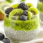 Layered Kiwi Chia Pudding In A Glass Topped With Fresh Berries And Toasted Coconut Flakes