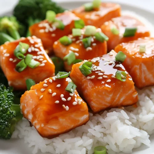 Delicious And Healthy Orange Salmon Bites Recipe 2 Delicious Orange Salmon Bites On White Plate With Rice And Broccoli, Garnished With Green Onions And Sesame Seeds