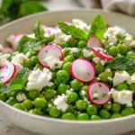 Pea Salad With Feta And Mint In A White Bowl, Garnished With Fresh Herbs And Drizzled With Olive Oil