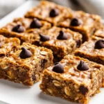 Plated Peanut Butter Banana Bars Drizzled With Chocolate Chips, Showcasing Their Soft Texture On A White Plate.