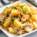 Pineapple Chicken Casserole Served On A White Plate, Topped With Crispy Noodles And Fresh Green Onions