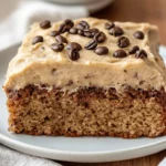Delicious Potluck Banana Cake Topped With Coffee Frosting On A White Plate, Adorned With Coffee Granules
