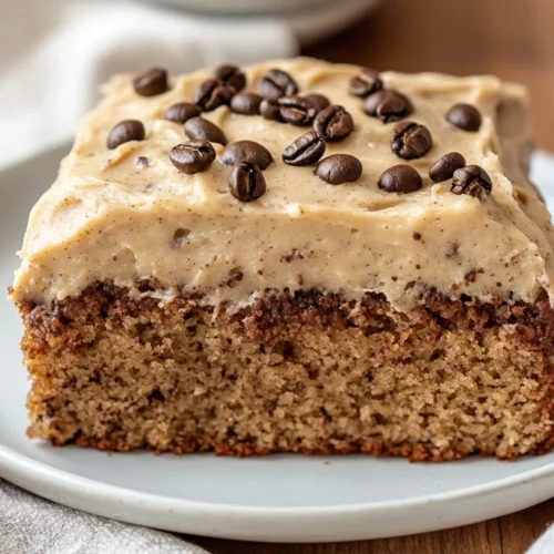 Potluck Banana Cake With Coffee Frosting (Easy &Amp; Moist Recipe) 2 Delicious Potluck Banana Cake Topped With Coffee Frosting On A White Plate, Adorned With Coffee Granules