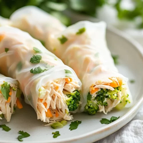 Delicious Slow Cooker Chicken Spring Rolls On A White Plate, Garnished With Cilantro And Served With Dipping Sauce