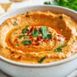 Bowl Of Spicy Roasted Red Pepper Feta Dip Topped With Olive Oil And Parsley, Served With Pita Chips