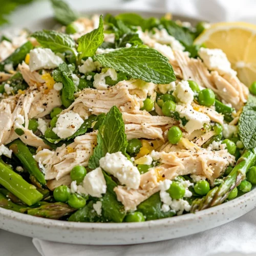 Spring Salad With Chicken And Lemon Dressing Served On A White Plate, Topped With Feta, Mint Leaves, And Lemon Slices