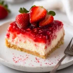 Strawberry Rhubarb Cheesecake On A White Plate Topped With Fresh Strawberries And Freeze-Dried Strawberry Dust