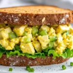 Tofu Egg Salad Sandwich On A White Plate With Fresh Lettuce And A Sprinkle Of Pepper