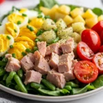 Colorful Tuna Nicoise Salad On A White Plate With Potatoes, Green Beans, And Hard-Boiled Eggs