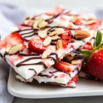 Delicious Vanilla Frozen Yogurt Bark On A White Plate Topped With Sliced Strawberries And Drizzled With Chocolate