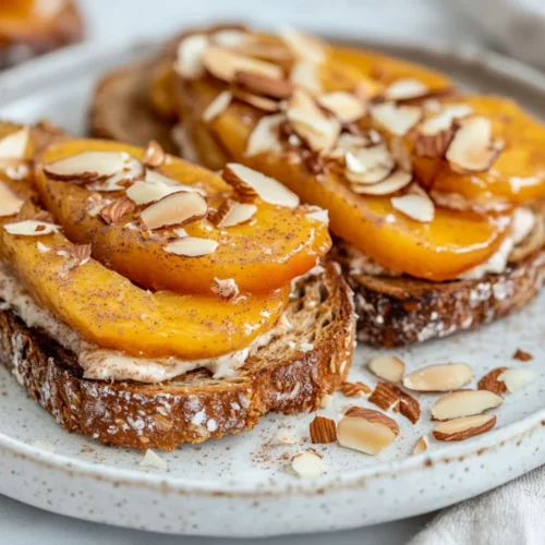 Almond Butter Toast With Peaches: A Healthy &Amp; Delicious Breakfast 2 Almond Butter Toast With Peaches, Cinnamon, Toasted Coconut, And Slivered Almonds On A White Plate