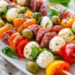 Colorful Antipasto Skewers On A White Plate With Mozzarella, Salami, Roasted Peppers, And Fresh Basil