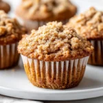 Delicious Banana Coffee Cake Muffins On A White Plate With Crumble Topping, Garnished With A Sprinkle Of Cinnamon