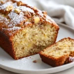 Moist Banana Pineapple Bread Served On A White Plate, Garnished With Walnuts And A Slice Cut Revealing Its Texture