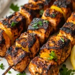 Blackened Salmon Skewers Served On A White Plate With Caramelized Lemon Slices And Fresh Parsley Garnish