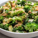 Broccoli Caesar Salad In A White Bowl Topped With Crispy Garlic, Panko Breadcrumbs, And Chives