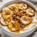 Caramelized Banana Yogurt Bowl Topped With Golden Bananas And Walnuts On A White Plate, Drizzled With Peanut Butter.