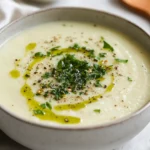 Bowl Of Creamy Cauliflower Soup With Herbs, Drizzled With Green Herb Oil And Topped With Dukkah