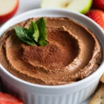 Creamy Chocolate Hummus Dip In A White Bowl Garnished With Cocoa Powder And Mint, Served With Fresh Fruits And Crackers