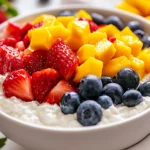 Cottage Cheese With Fruit Topped With Strawberries And Mango In A White Bowl, Drizzled With Honey