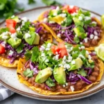 Colorful Easy Tostadas With Refried Beans Topped With Avocado, Lettuce, And Cotija Cheese On A White Plate